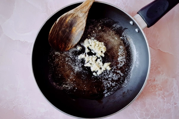 Butter, chopped garlic and oil in a skillet with a wooden ladle