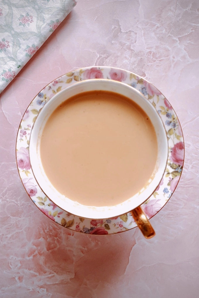 Japanese royal milk tea in a teacup over a saucer with a paper napkin in the top left corner