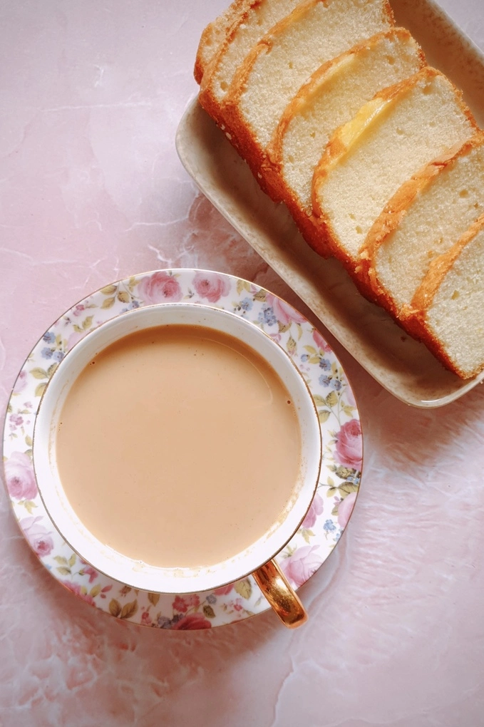 Japanese royal milk tea in a teacup over a saucer with slices of butter cake on a square plate next to it