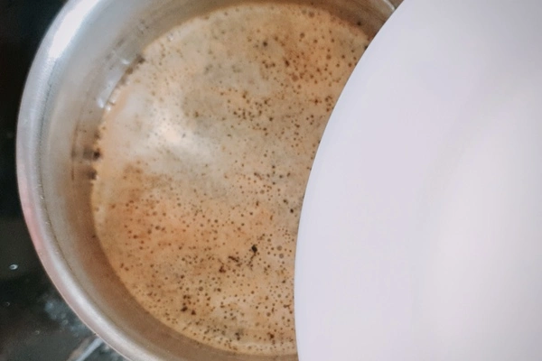 Japanese royal milk tea in a saucepan partially covered by a white plate