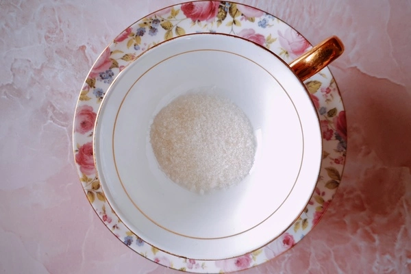 A teacup with a little sugar in it over a saucer