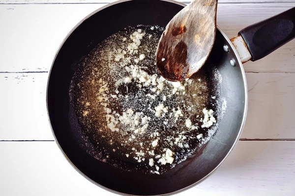 Butter, oil and minced garlic in skillet with a wooden ladle