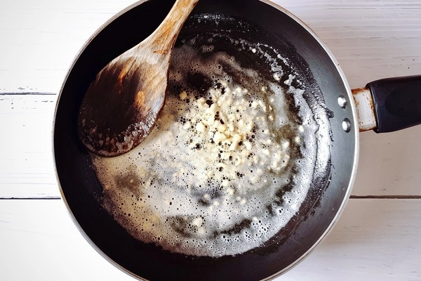 Butter, oil and golden brown minced garlic in skillet with a wooden ladle