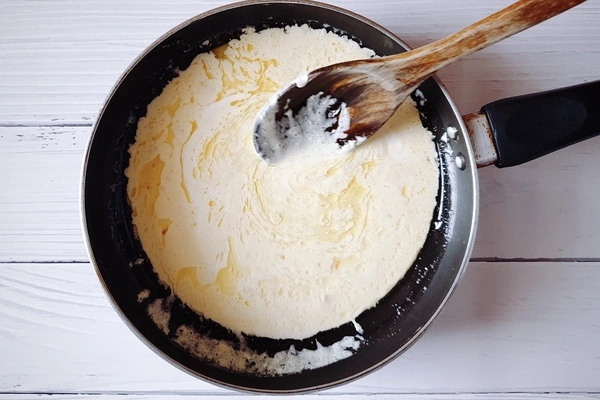Butter, oil, minced garlic and cream in a skillet with a wooden ladle