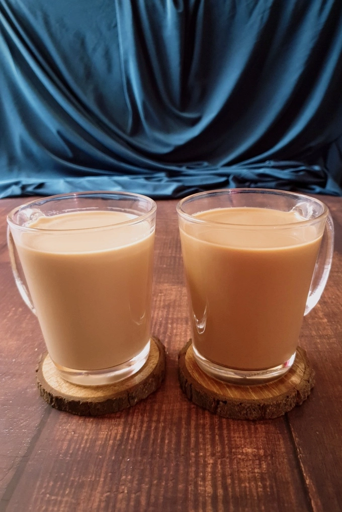 Royal milk tea vs milk tea in two glass mugs on wooden coasters