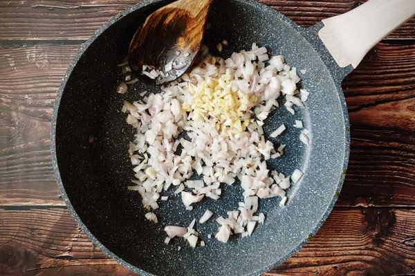 A skillet with a little oil, diced onions and chopped garlic in it
