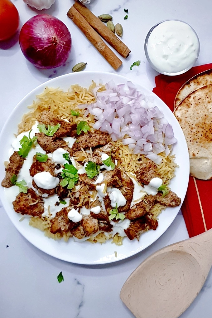 Chicken Shawarma with Garlic Sauce Rice on a white plate served with chopped onions on the side