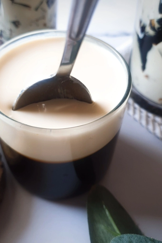 Close up of Homemade Coffee Jello Recipe with Condensed Milk Cream in a small glass with a spoon inserted in it