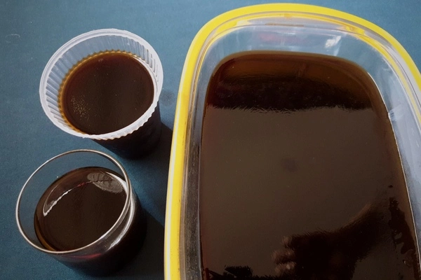 Liquid mixture of black cofee and gelatin poured into two glass shaped molds on the left and also in a glass tray on the right