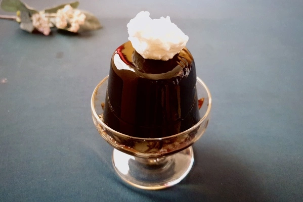 Coffee Jello in a dessert bowl with a dollop of whipped cream on top