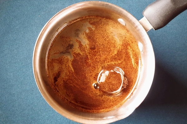 Top view of a saucepan with water and instant coffee powder in it
