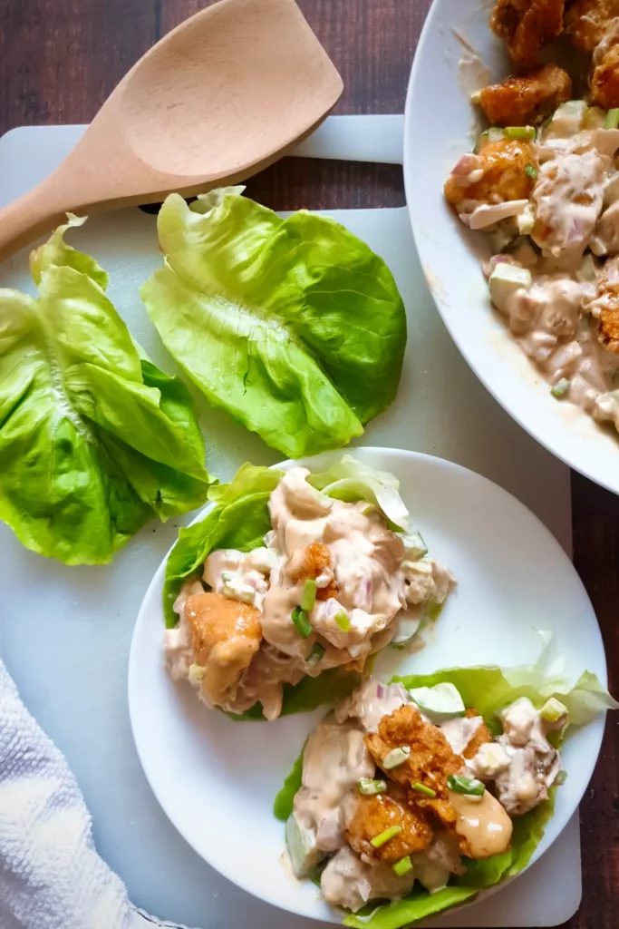 Gluten free chicken salad recipe being prepared in lettuce cups with the help of a wooden ladle.